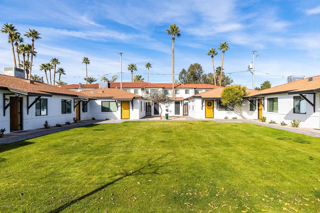 a group of houses with a green lawn and palm trees