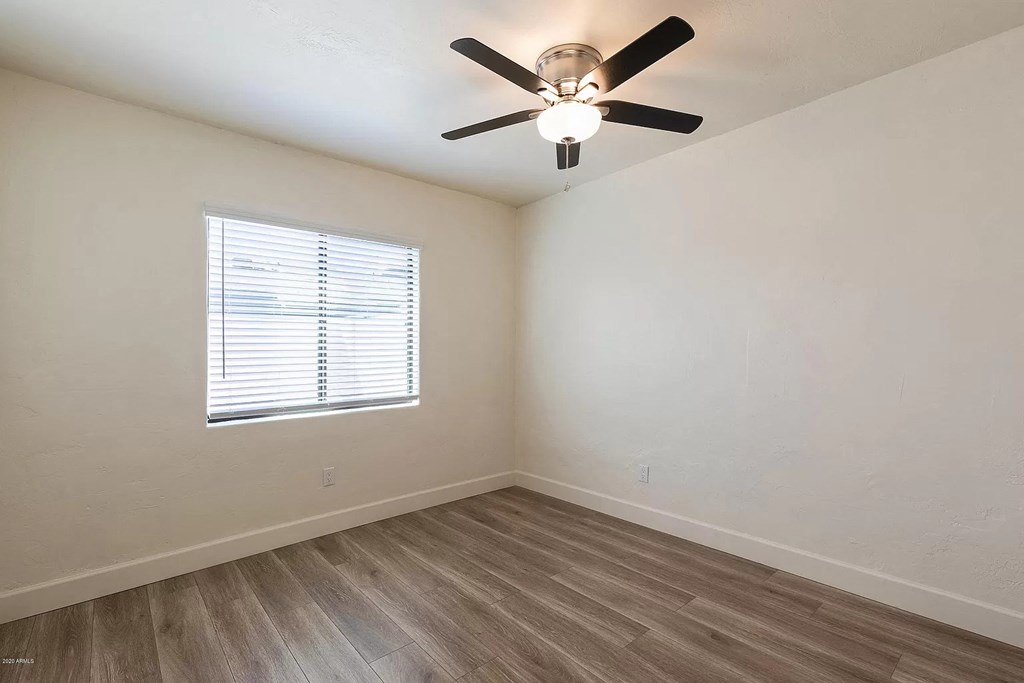an empty room with a ceiling fan and a window