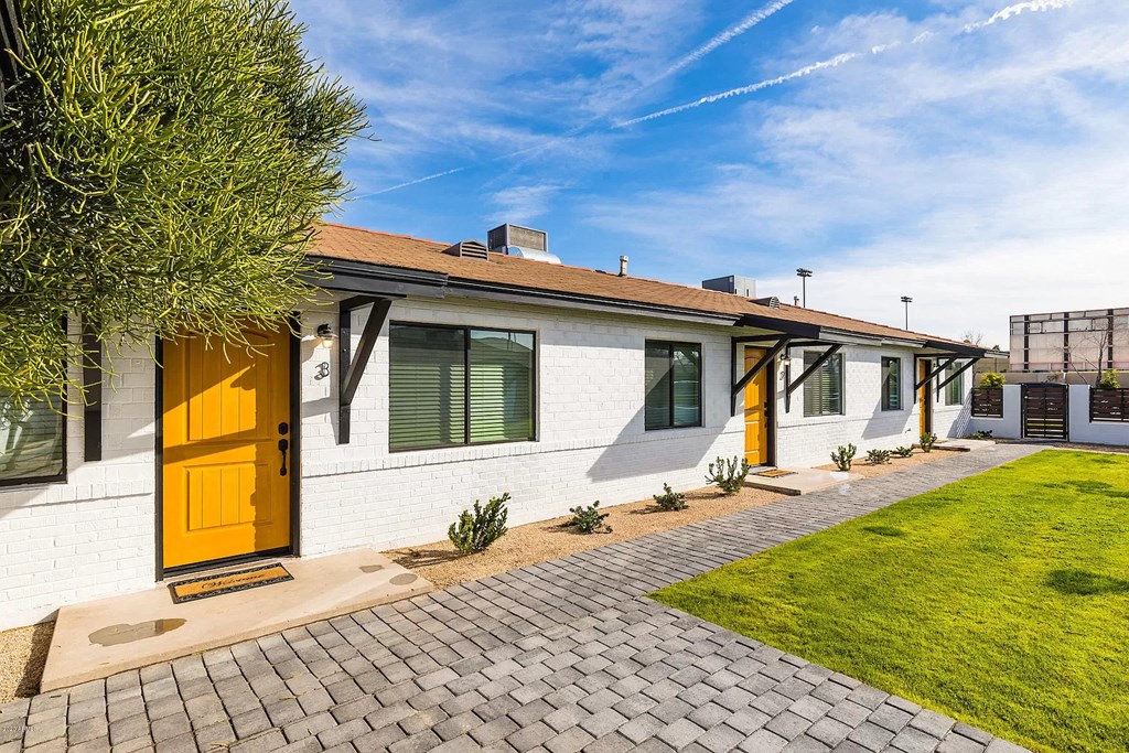 the front of a white house with yellow doors