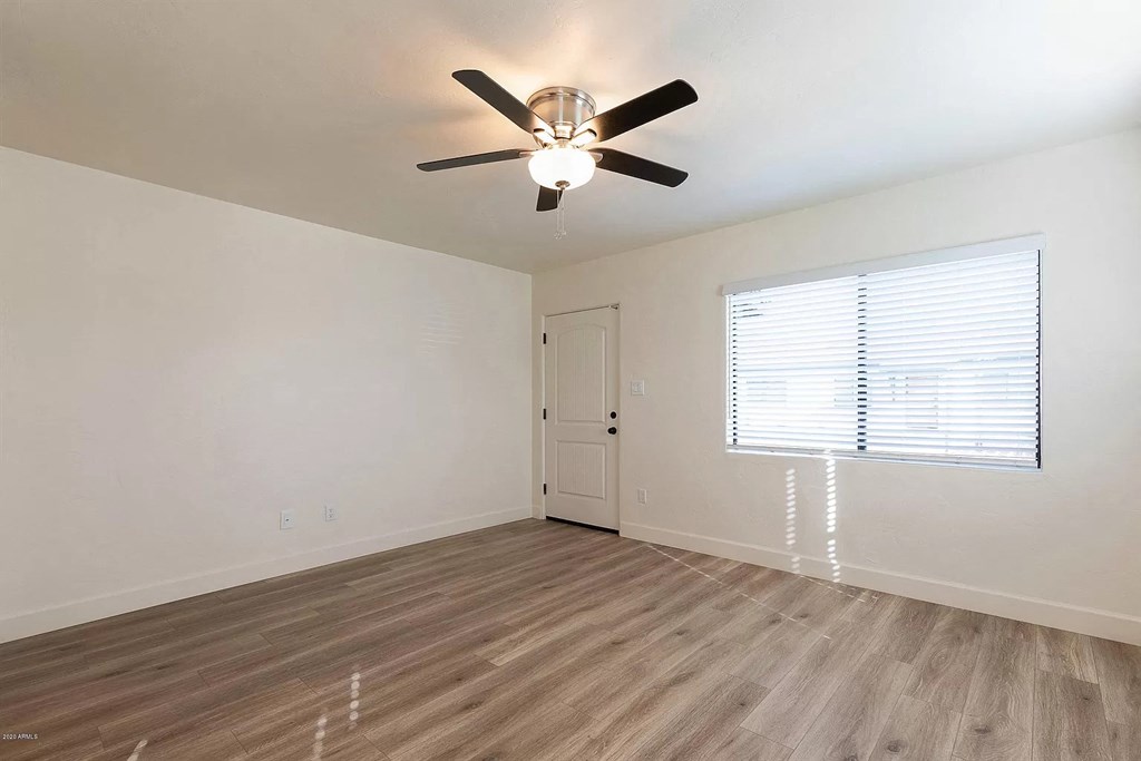 an empty living room with a ceiling fan and a window