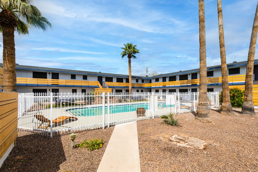 A pool surrounded by a fence and palm trees.
