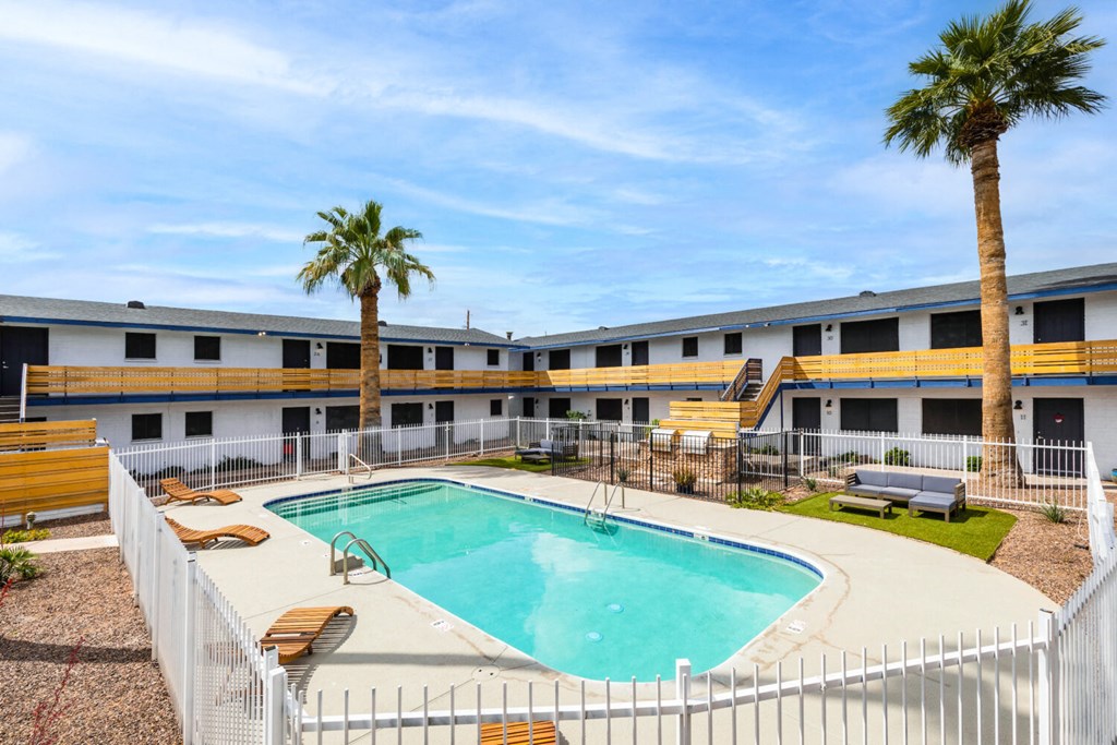 A pool surrounded by a white fence with a palm tree in the background.