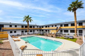 A pool surrounded by a white fence with a palm tree in the background.