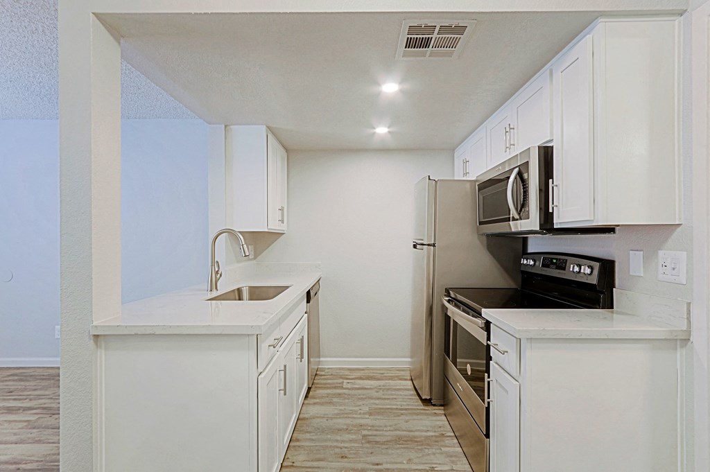 an empty kitchen with white cabinets and stainless steel appliances