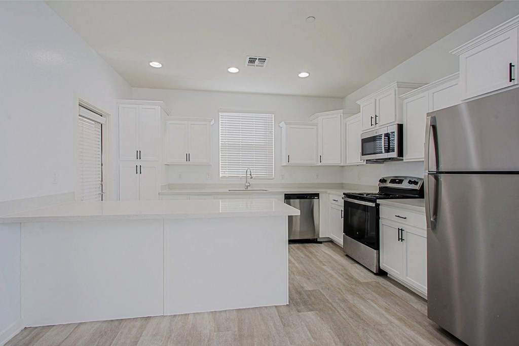 an empty kitchen with white cabinets and stainless steel appliances