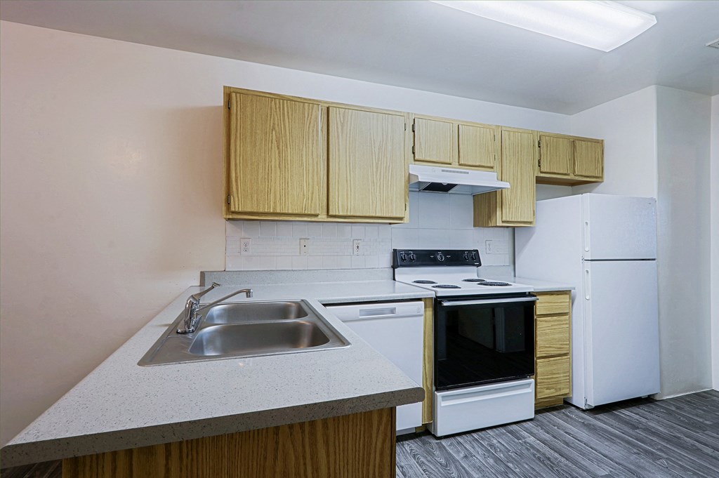 A kitchen with a white refrigerator, stove, and sink.