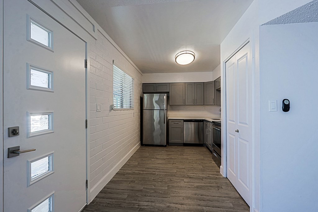 A kitchen with white walls and a wooden floor.