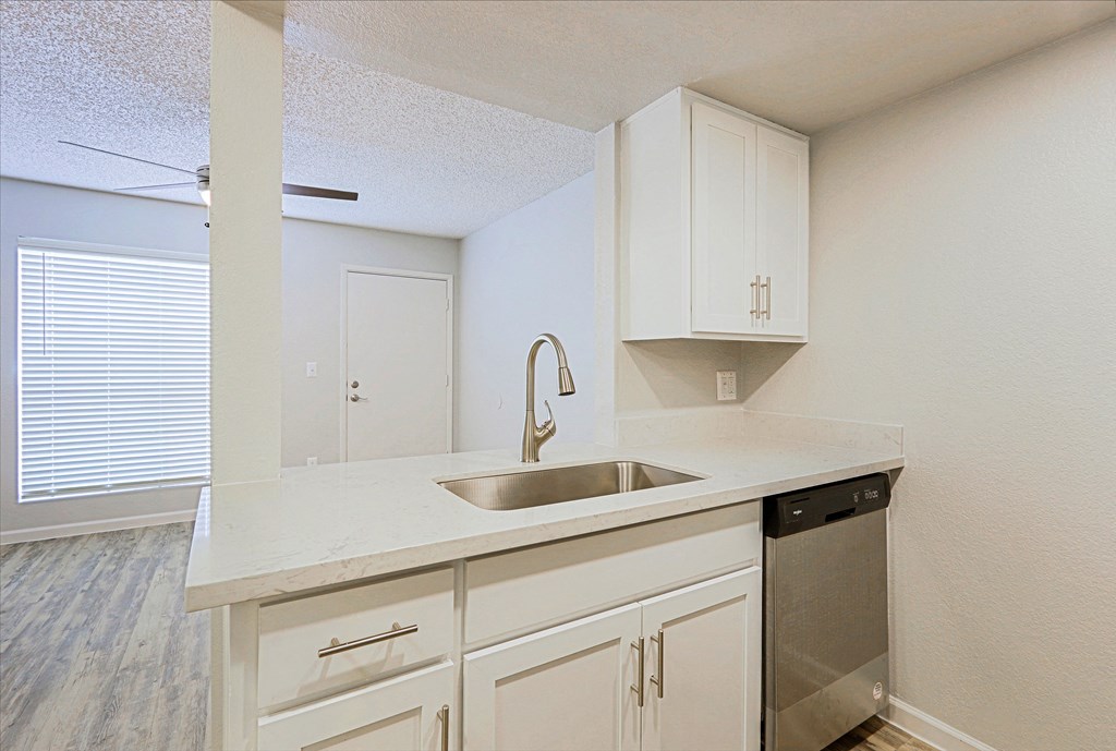 an empty kitchen with white cabinets and a sink