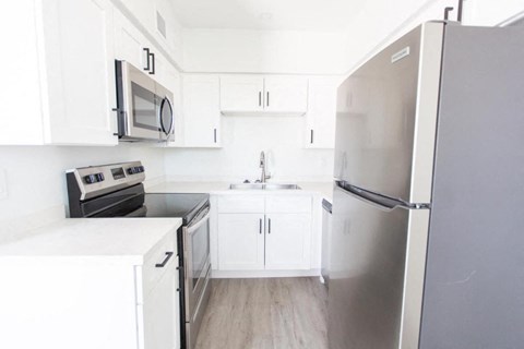 a white kitchen with stainless steel appliances and white cabinets