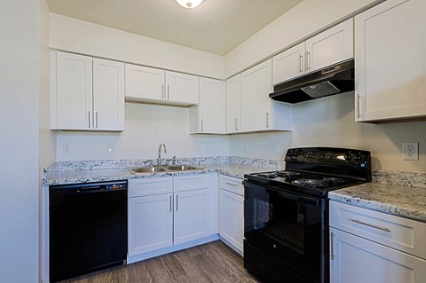 A kitchen with white cabinets and black appliances.