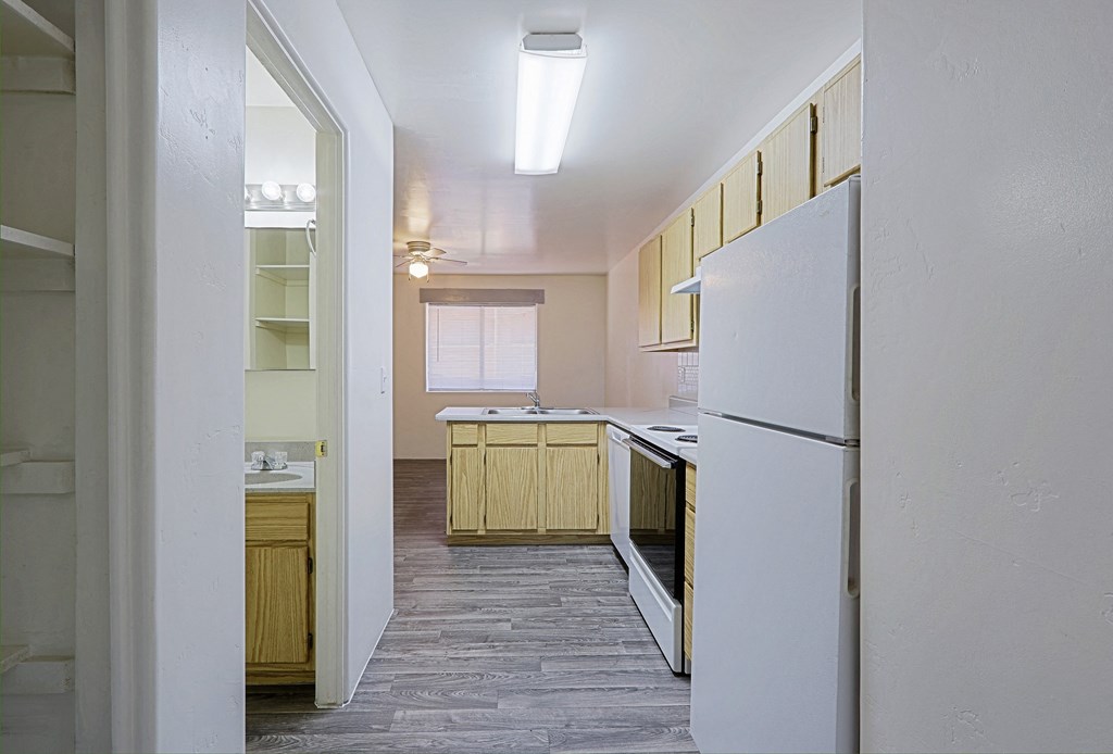 A kitchen with a white refrigerator and wooden cabinets.