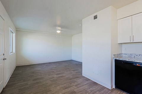 A kitchen area with a black fridge and wooden flooring.
