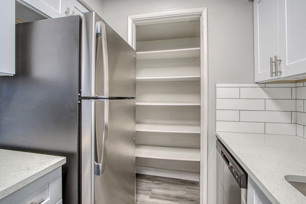 an empty pantry in a kitchen with a stainless steel refrigerator