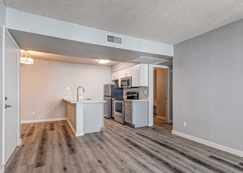 A kitchen with white cabinets and a wooden floor.