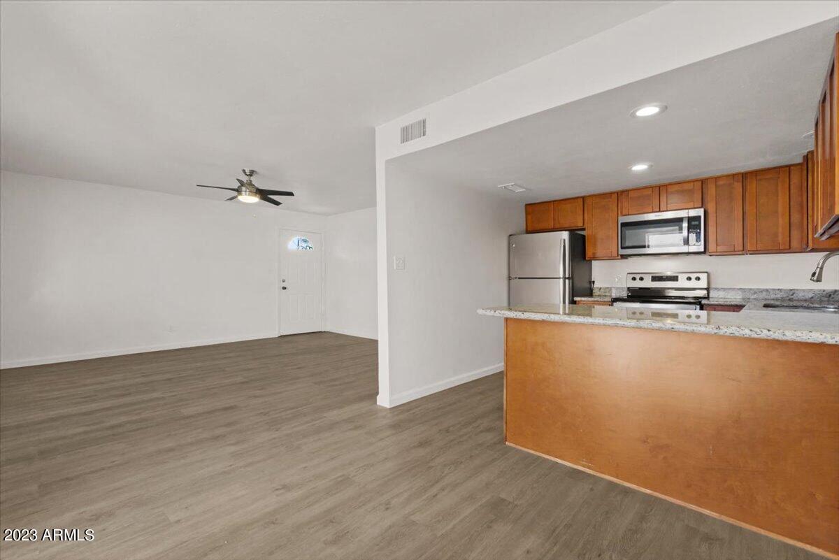 an empty living room with a kitchen and a counter top