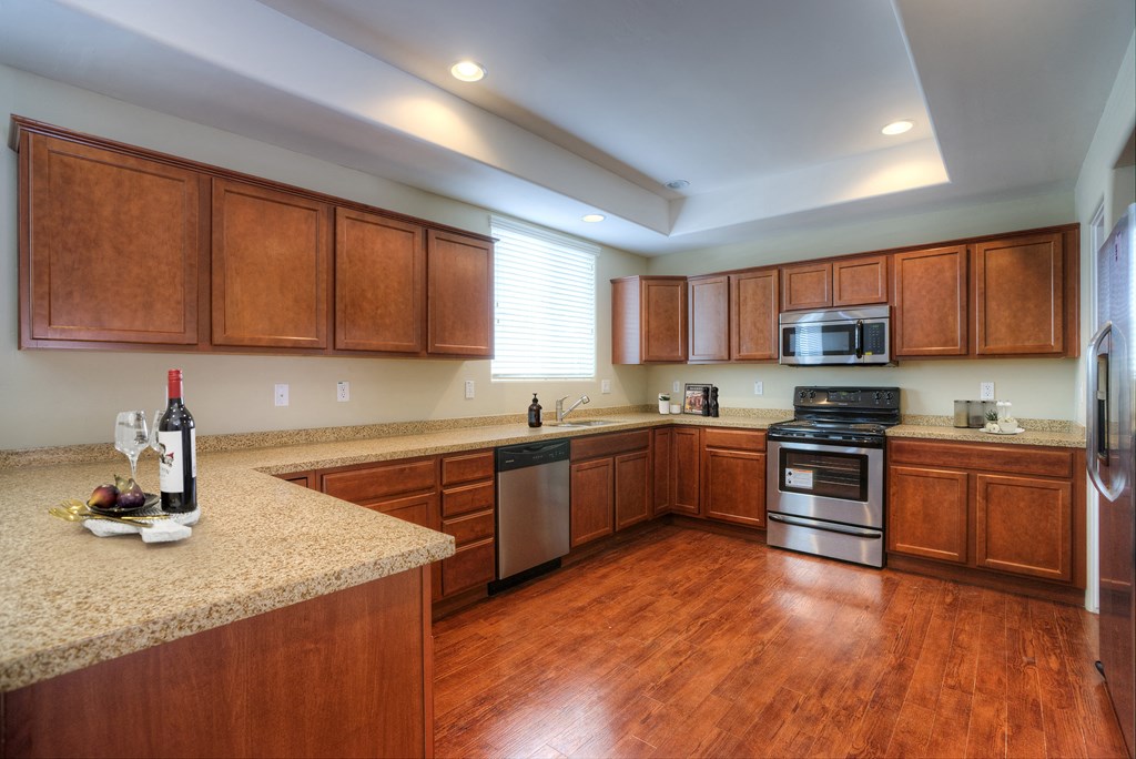 a kitchen with wooden cabinets and granite counter tops and a stainless steel stove and microwave