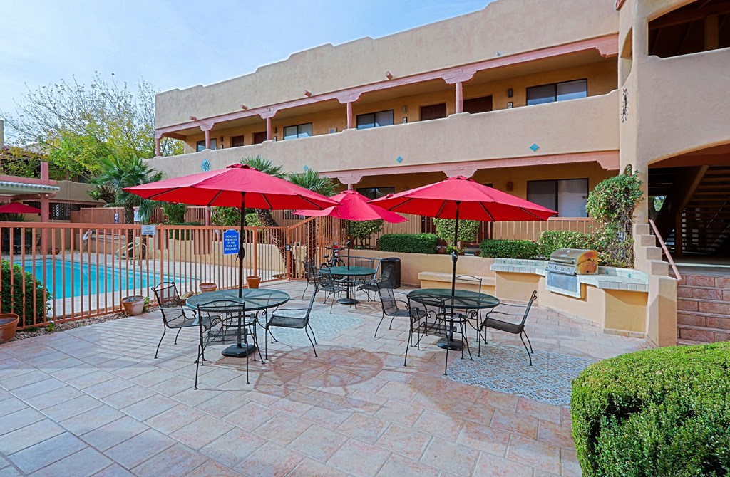 A patio with tables and chairs and umbrellas.