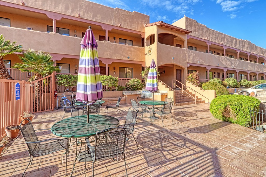 a patio with tables and umbrellas in front of a hotel