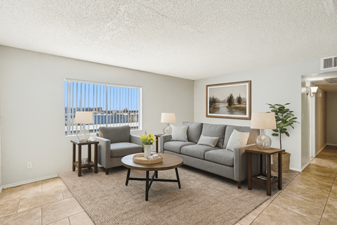 A living room with a grey couch, a coffee table, and a painting on the wall.