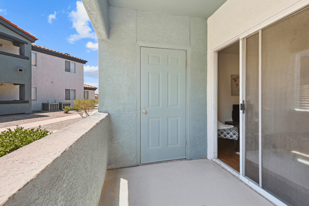 a patio with a blue door and a bathroom in the background
