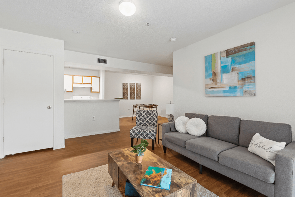 a living room with a couch coffee table and a kitchen in the background