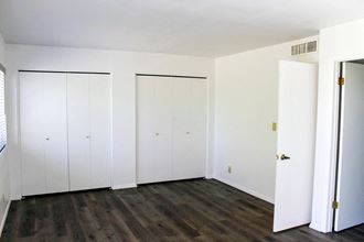 an empty room with white closets and a wooden floor