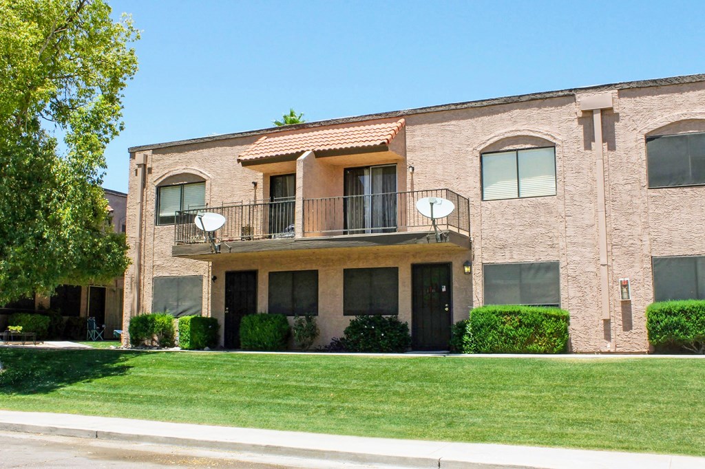a brick building with a balcony and a lawn