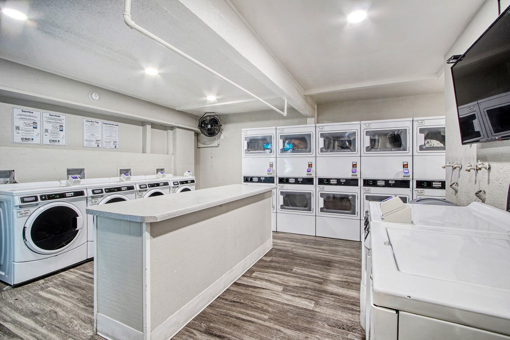 a laundry room with washer and dryers and a counter top and a sink