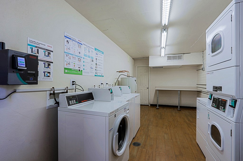 A laundromat with washers and dryers and a wall of posters.