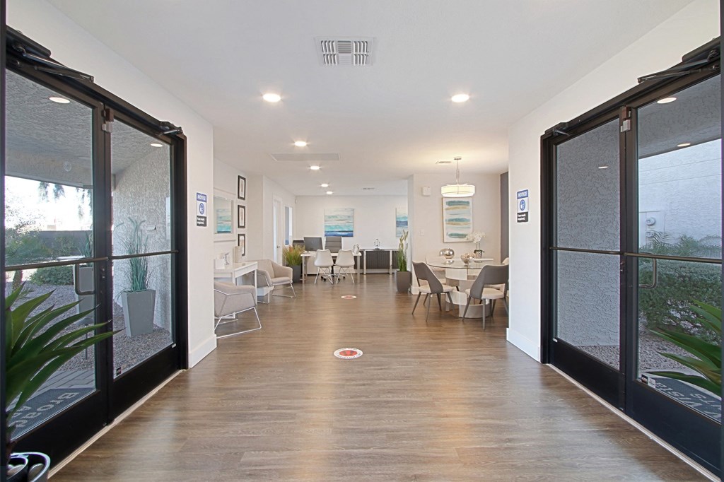 a corridor with glass doors and tables and chairs in a building