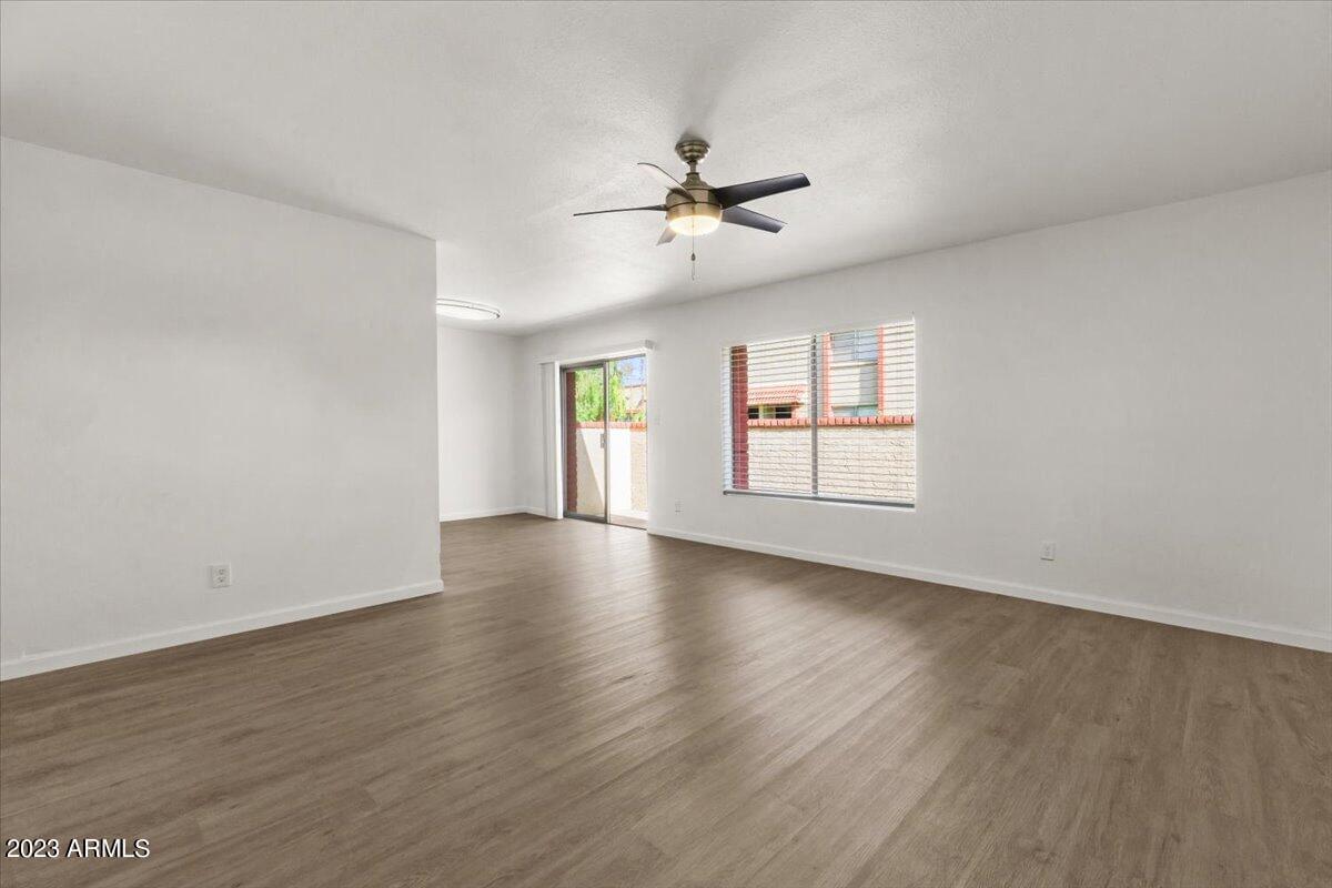 an empty living room with a ceiling fan and a window