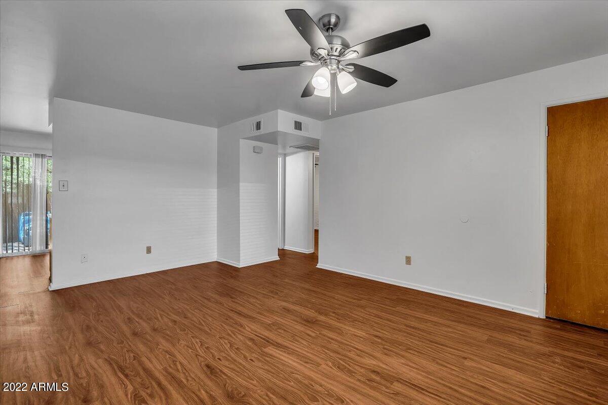 A room with a ceiling fan and wooden flooring.