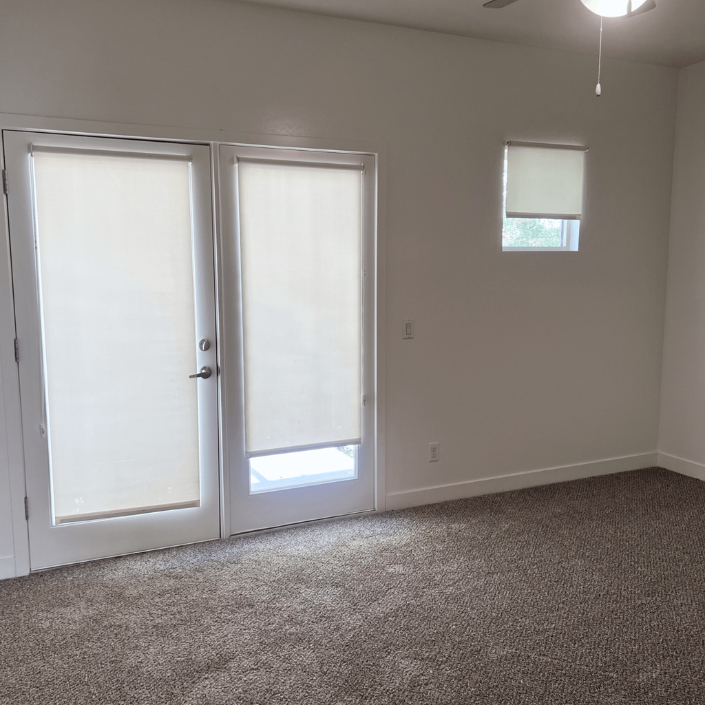 an empty room with two doors and a window