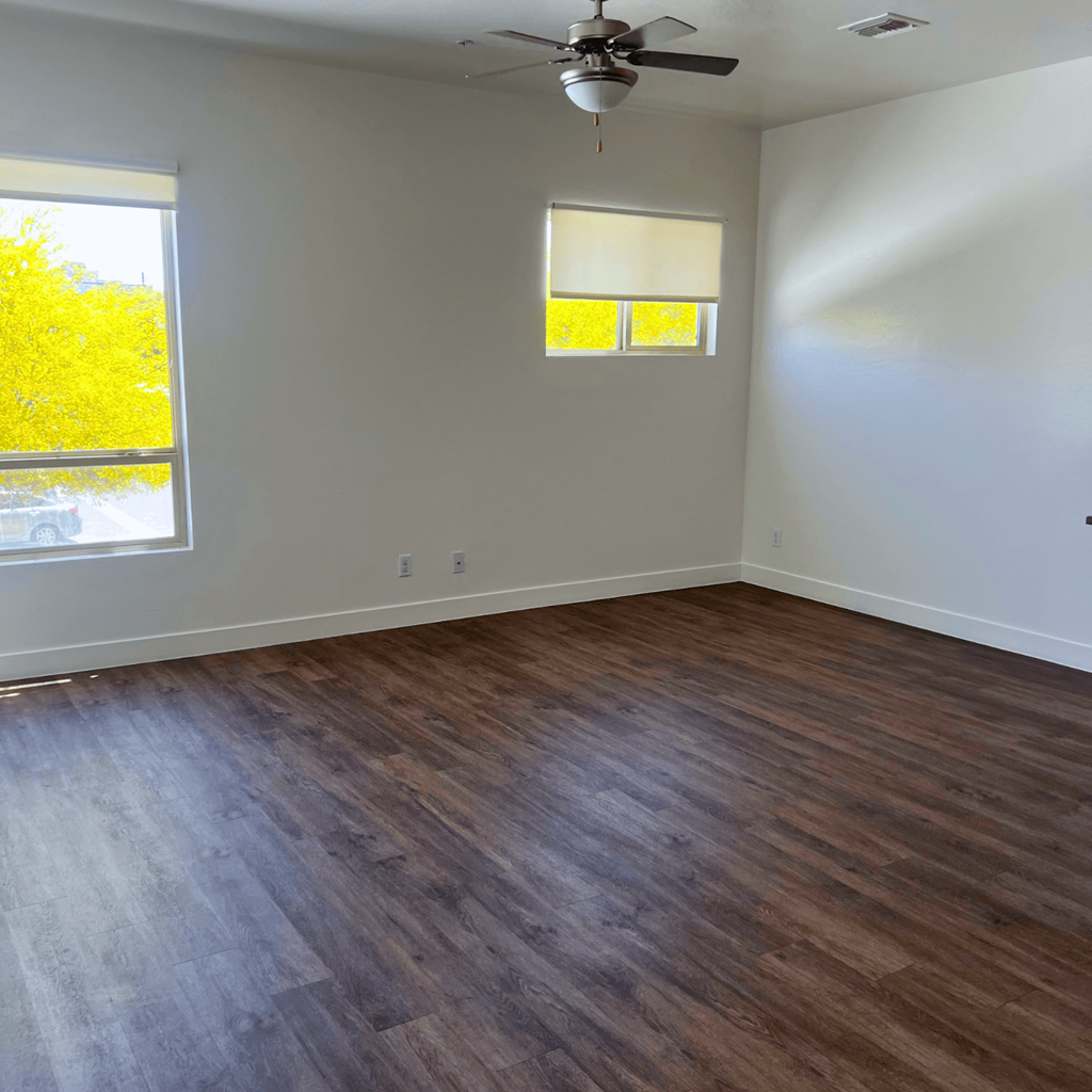 an empty living room with wooden floors and a ceiling fan