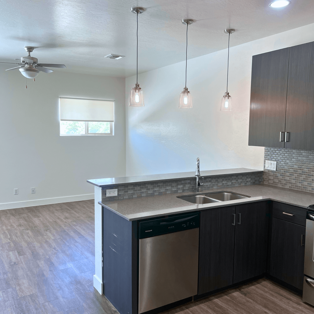 an empty kitchen with dark cabinets and a stainless steel sink