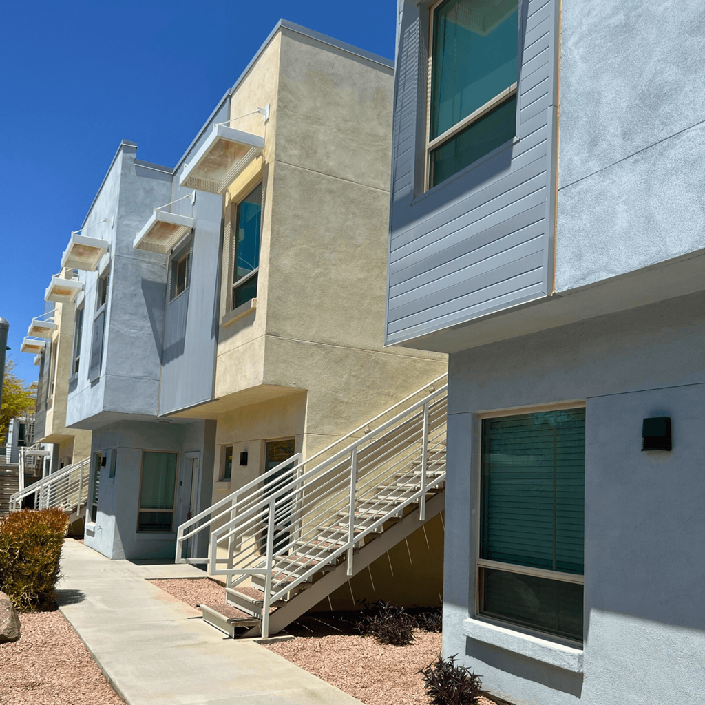 a row of apartments with stairs and balconies on a sunny day