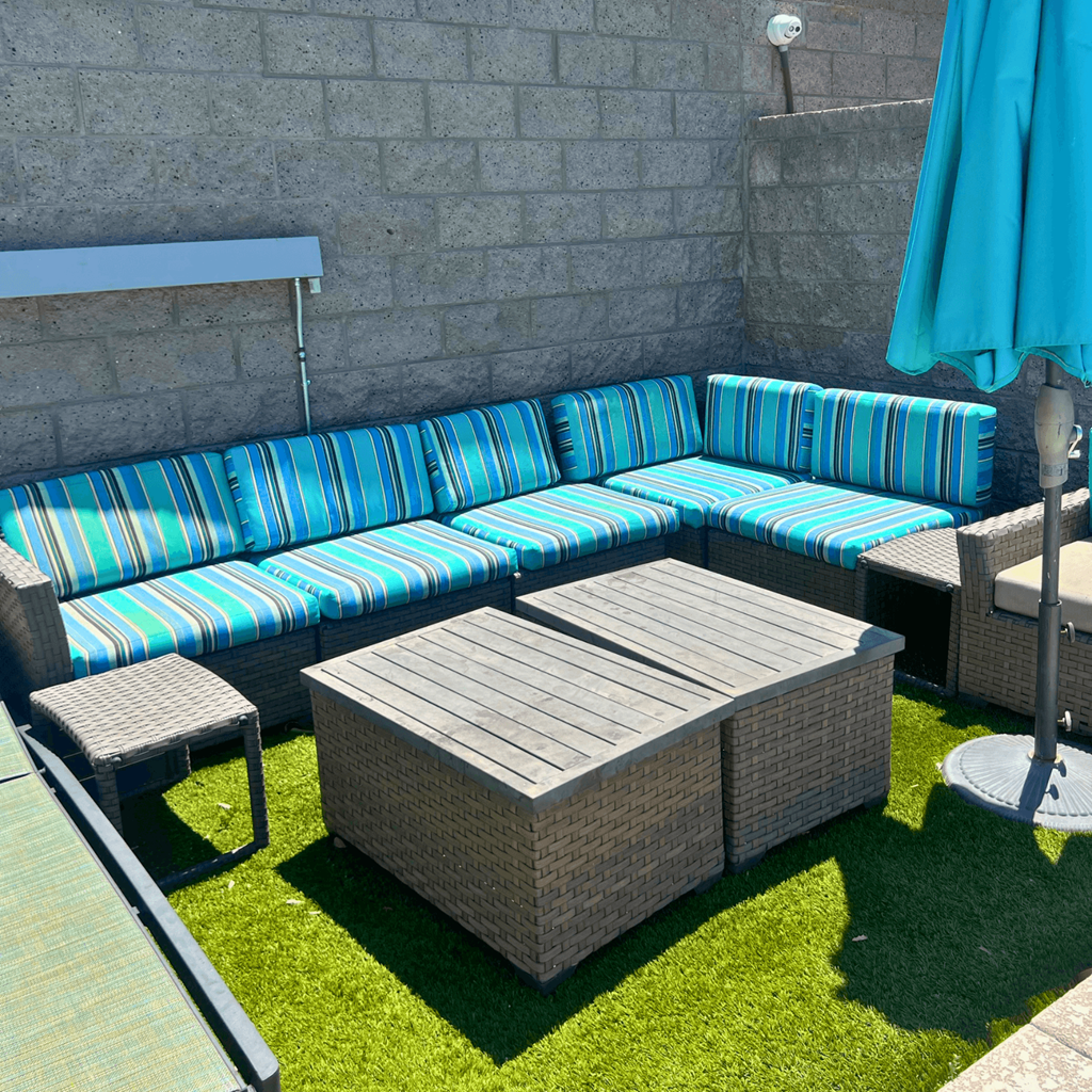 a patio with a couch and tables and an umbrella
