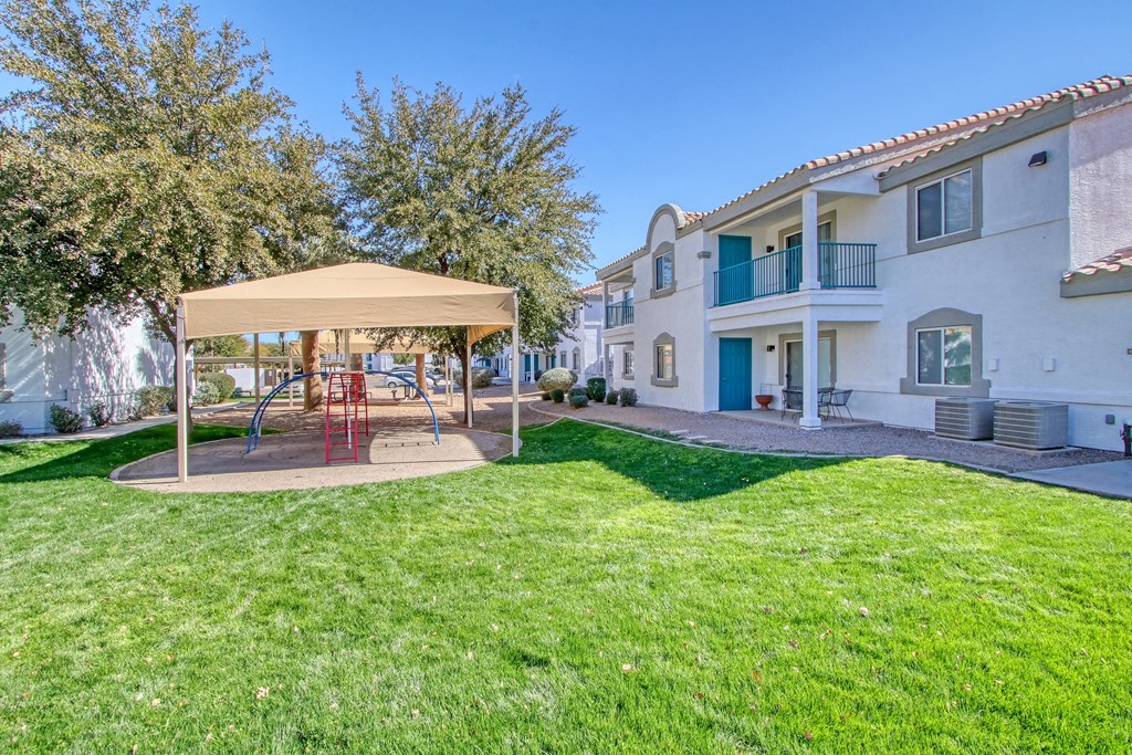 the backyard of a house with a playground and a gazebo