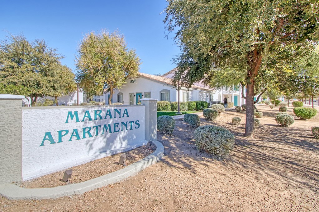 a sign apartments in front of trees and a building