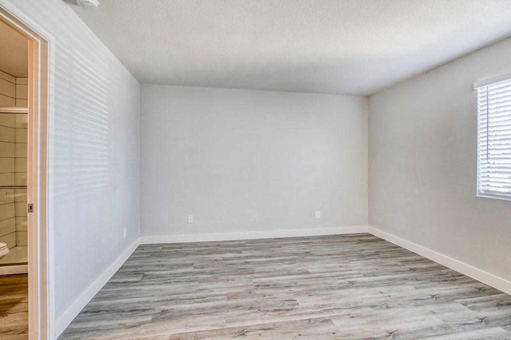 an empty bedroom with wood flooring and white walls