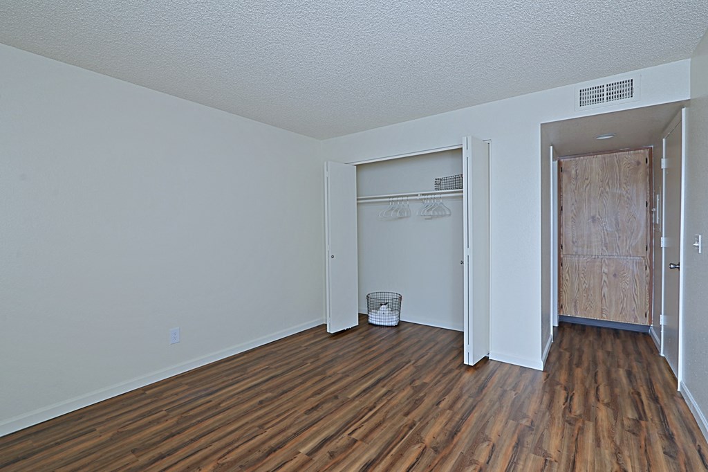 a bedroom with hardwood floors and a closet with an open door