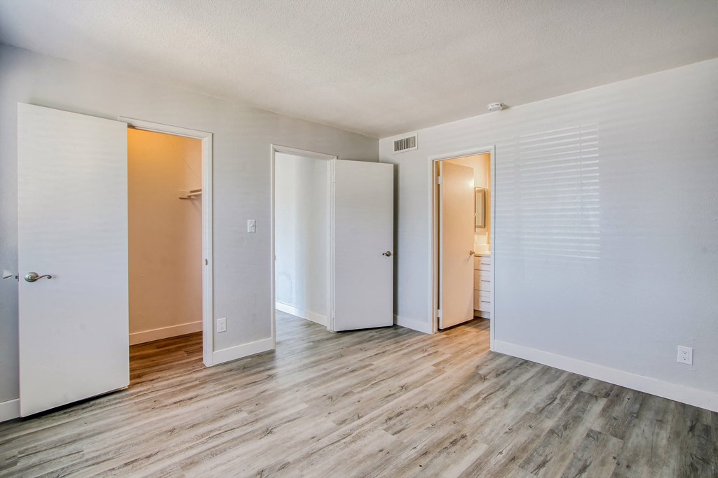 the living room of an apartment with wood floors and white walls