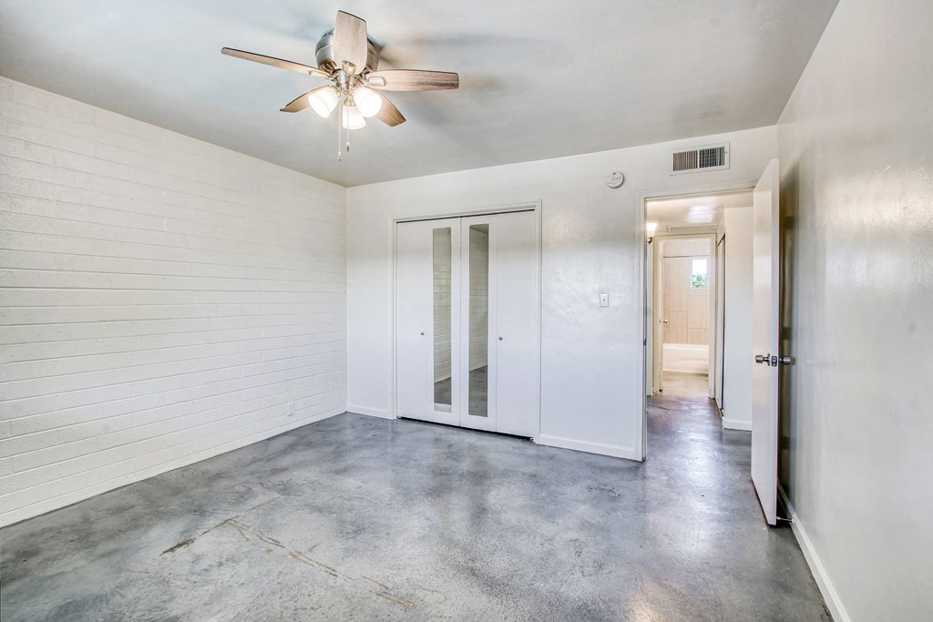 a bedroom with white walls and a ceiling fan