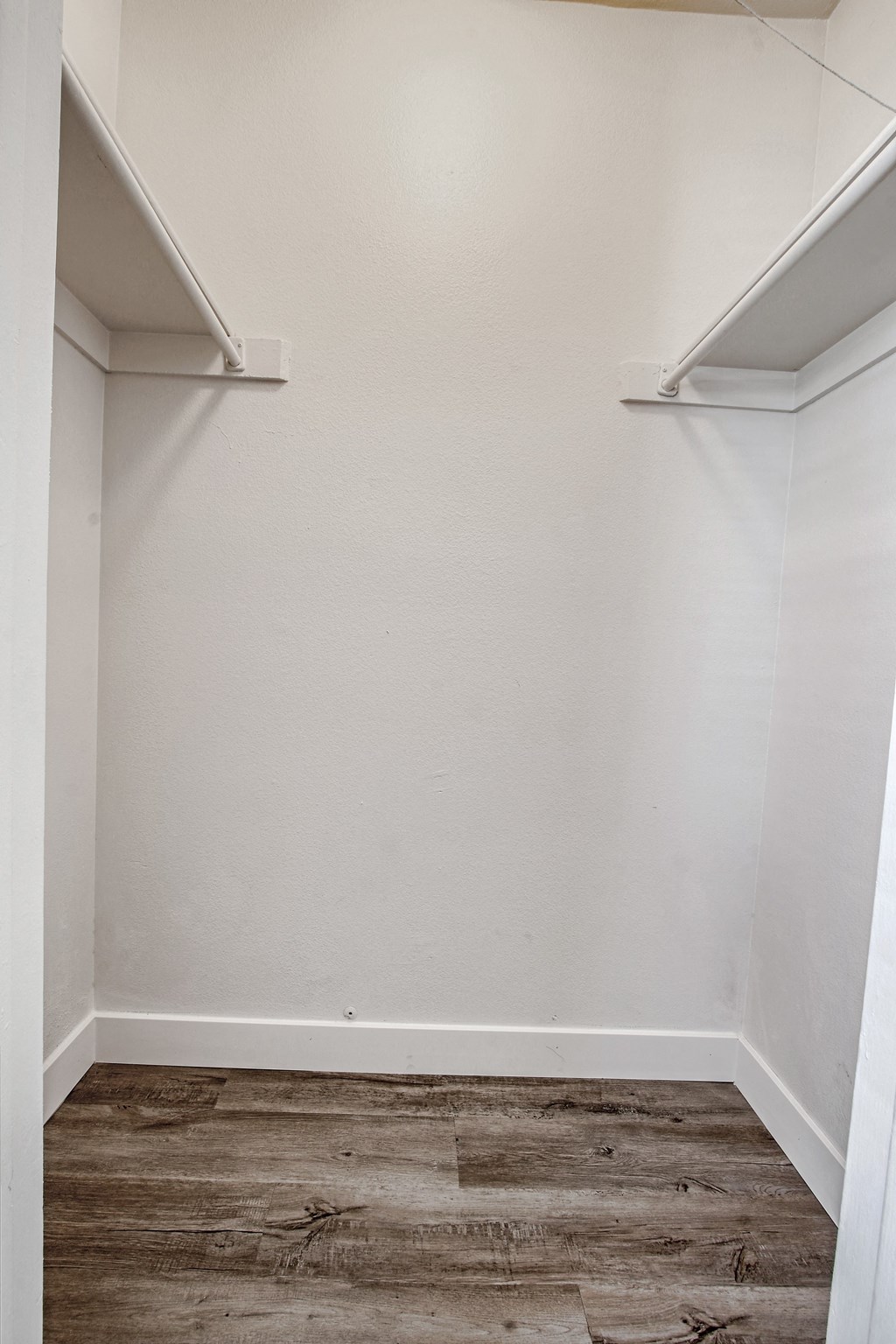 an empty closet with a wood floor and white walls