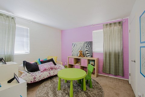 a room with pink walls and a green table and chairs