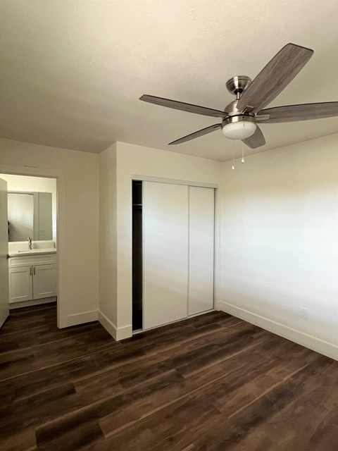 an empty living room with a ceiling fan and a closet