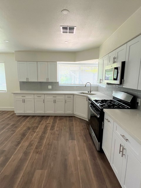 a kitchen with white cabinets and a stove and a sink