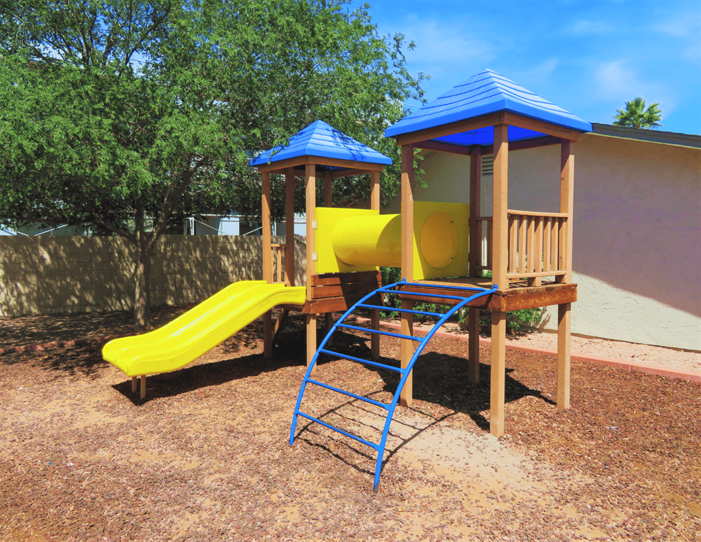 a playground with a yellow slide and a blue monkey bars