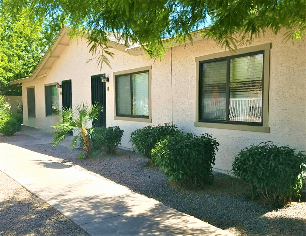 a building with three windows and a sidewalk in front of it