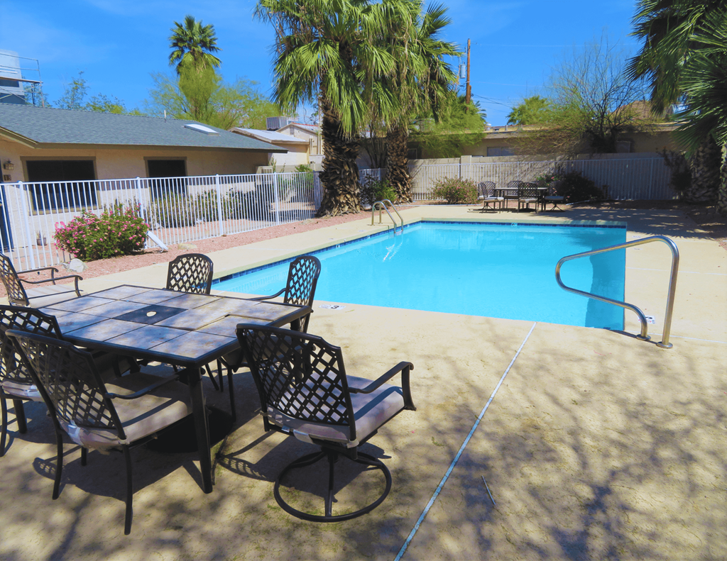 a patio with a table and chairs next to a swimming pool